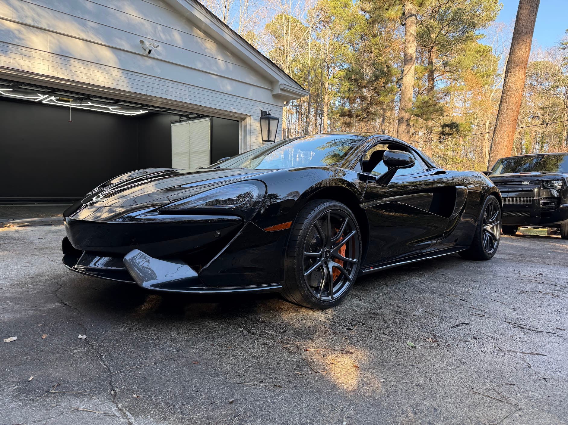 Freshly detailed black McLaren 570S in a Raleigh driveway