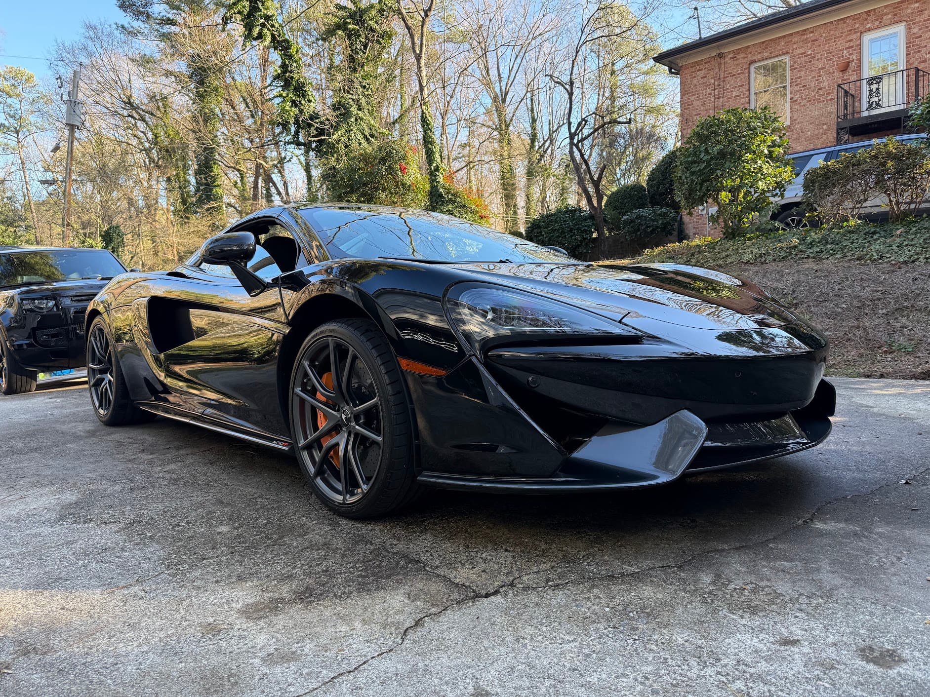 Black McLaren 570S with a Land Rover Defender behind it after mobile detailing